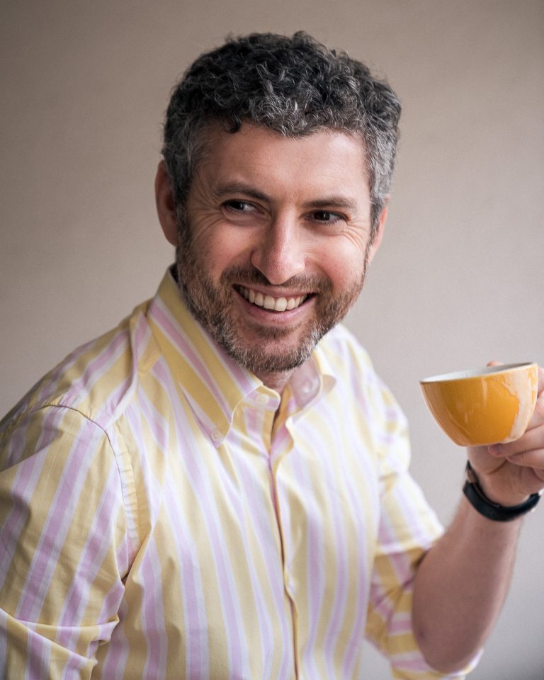 Portraitfoto von lachendem Gentleman mit Kaffeetasse in der Hand
